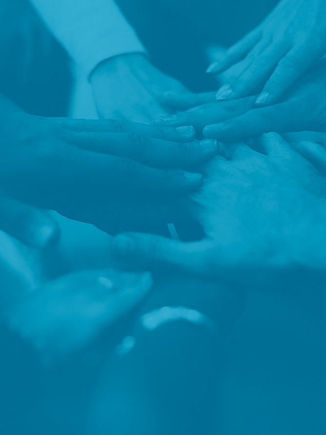 Multiple hands gently placed on a person's stomach, suggesting a medical or therapeutic setting.